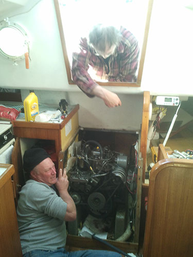 Kevin works to remove an access hatch while Tom looks on.