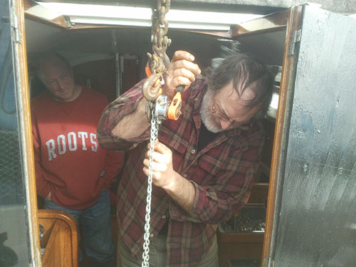 Tom hoists the mighty Yanmar 2QM15 (15 hp diesel engine) while Kevin looks on.